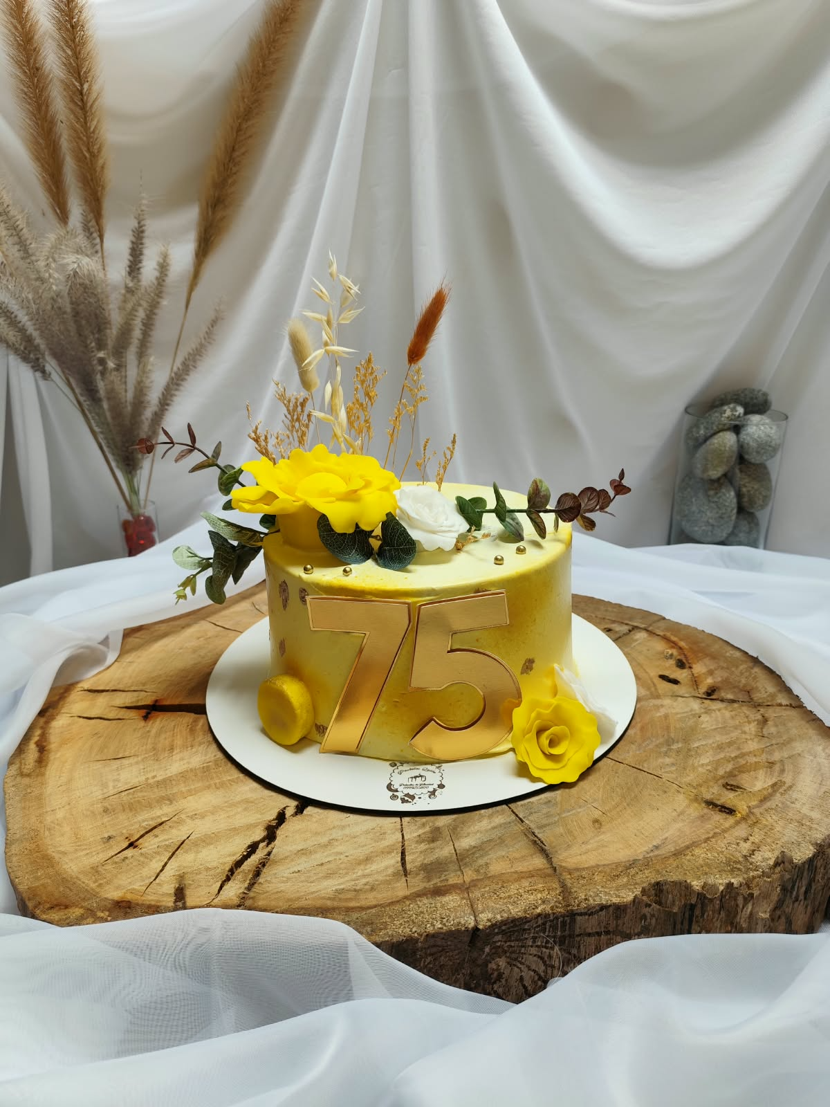 Pastel amarillo con número 75 dorado y flores
