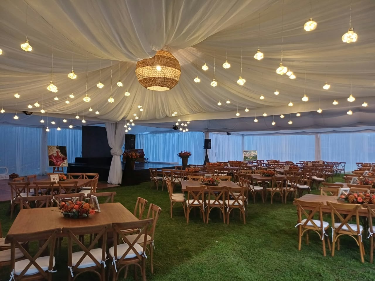 Salón decorado con luces colgantes y mesas de madera servidas