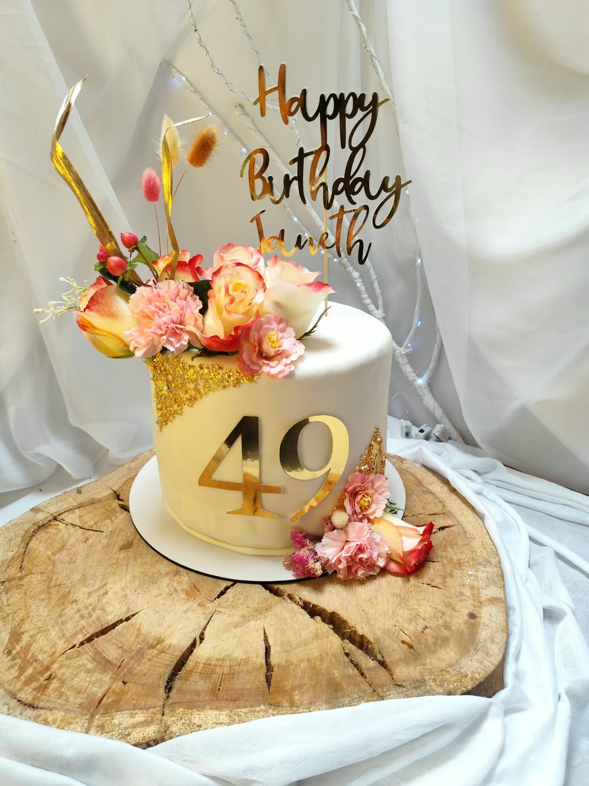 Pastel de cumpleaños blanco con flores rosadas, número 49 dorado y topper Happy Birthday Janeth